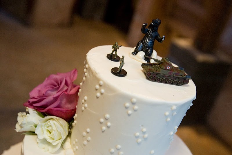 tiny godzilla and tank on top of wedding cake
